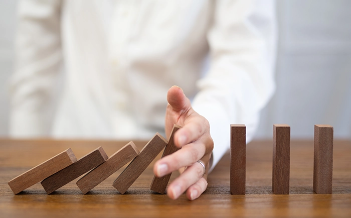 ドミノを止めて、リスクを防ぐように見せている写真