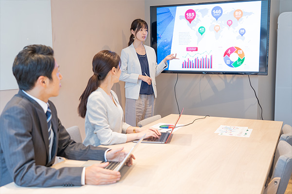 若いスタッフ（女性）がドキュメントを使ってプレゼンしているイメージ